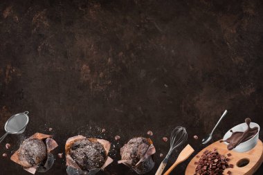 Çikolatalı kekler ya da kahverengi arka planda mutfak aletleri olan kekler. Boşluğu kopyala.