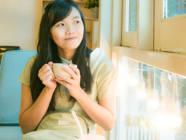 Asian beautiful young woman drinking coffee near window — Stock Photo, Image