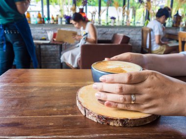 Yüzüklü bardak kahve rustik ahşap masa arka planda tutan eller