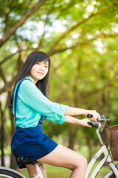 Asiatisk söt kvinna med cykel i trädgården. — Stockfoto