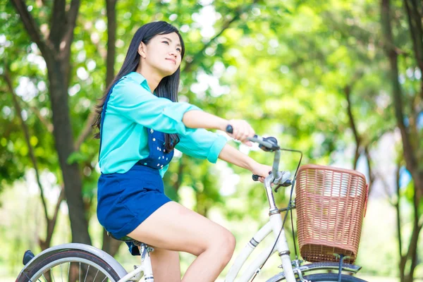 Asiático bonito mulher com bicicleta no jardim . — Fotografia de Stock