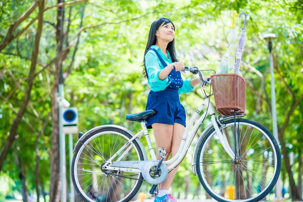 Миленькая азиатка с велосипедом в саду . — стоковое фото