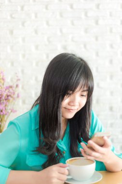 Bir fincan kahve ile cep telefonu kafede, sanat geç kahve dükkanı tutan kadın