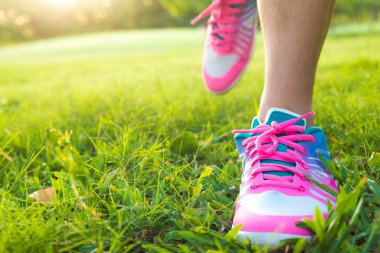 Çimenlerin üzerinde çalışan genç bayan çalıştıran jogger bacaklar görünümünü