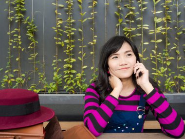 Mobil akıllı telefon kullanan gülümseyen Asyalı kadın.