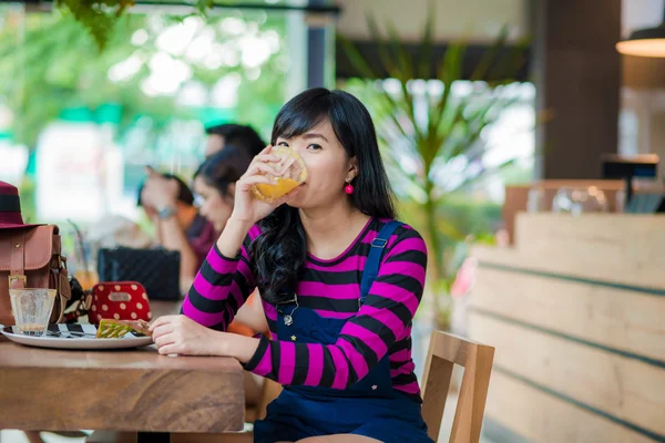 Молодая азиатская красивая женщина пьет свежий апельсиновый сок — стоковое фото