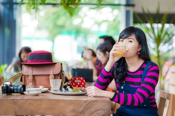 Азиатка, держащая стакан апельсинового сока в кафе — стоковое фото