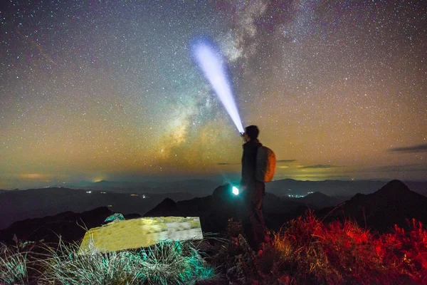 Hiker standing next to the Milky Way galaxy pointing — Stock Photo, Image