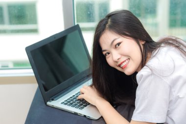 Genç Asyalı kadın erken sabah yatakta condominiumfrom, dizüstü bilgisayar kullanarak