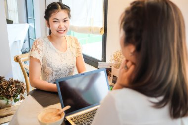 Gülümseyen kadın arkadaş sıcak içecek iş kurmak için kafede dizüstü kullanarak grubu