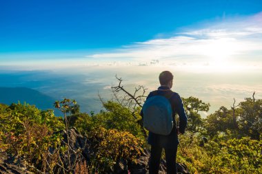 Dağların tepesinde bir fotoğrafta sırt çantası ile genç adam