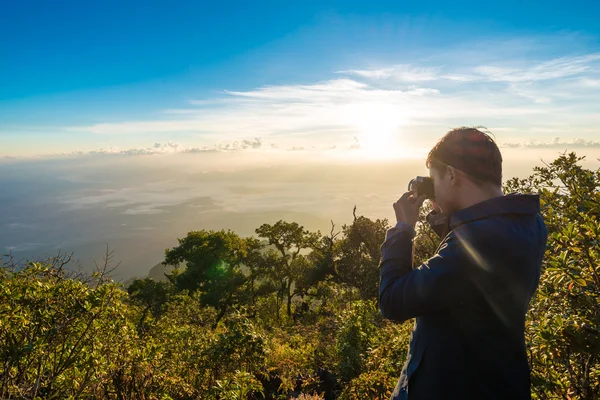 Young man with backpack taking a photo on the top of mountains — Stock Photo, Image