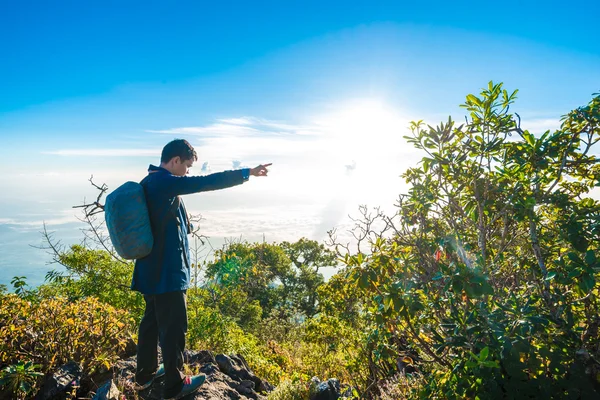 Joven con mochila tomando una foto en la cima de las montañas — Foto de Stock