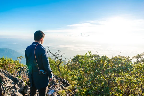 Jovem com mochila tirando uma foto no topo das montanhas — Fotografia de Stock