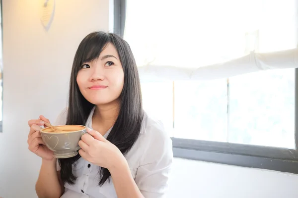 Asian woman drinking coffee and hold cup near window — Stock Photo, Image