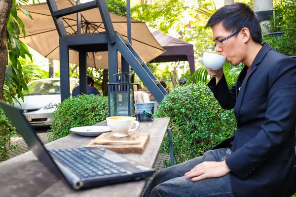 カフェショップでコーヒーカップとノートパソコンで働くビジネスマン — ストック写真