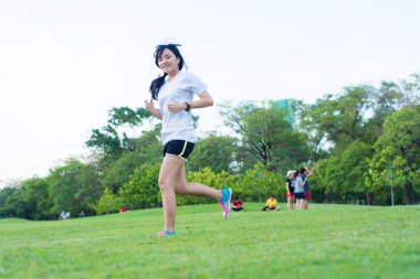 Şehrin Central Park 'ında koşan ve egzersiz yapan Asyalı genç bir kadın, Asya spor zindeliği.