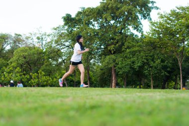 Şehrin Central Park 'ında koşan ve egzersiz yapan Asyalı genç bir kadın, Asya spor zindeliği.
