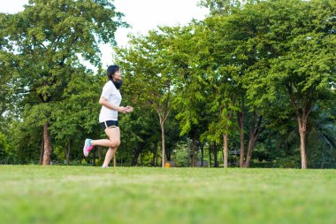 Şehrin Central Park 'ında koşan ve egzersiz yapan Asyalı genç bir kadın, Asya spor zindeliği.