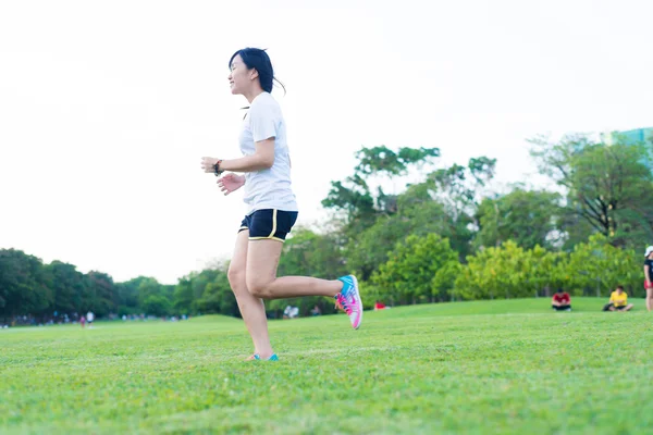 Parkta koşan genç fitness kadını yeşil çimlerde, spor yapan kadınlar.