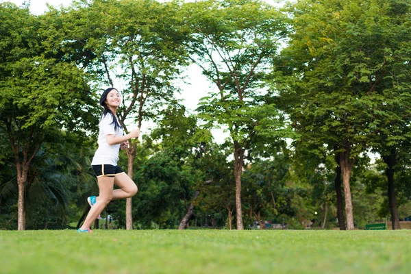 Şehrin Central Park 'ında koşan ve egzersiz yapan Asyalı genç bir kadın, Asya spor zindeliği.