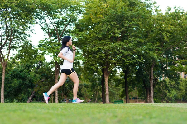 年轻的健身女人在绿草上运行在公园 — 图库照片