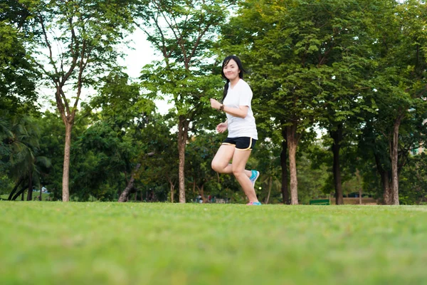 年轻的健身女人在绿草上运行在公园 — 图库照片