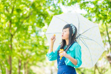 Genç Asyalı kadın kabarcıklar yeşil park açık havada üfleme