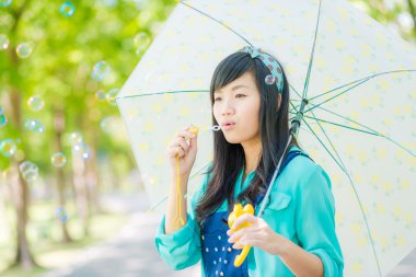 Genç Asyalı kadın kabarcıklar yeşil park açık havada üfleme