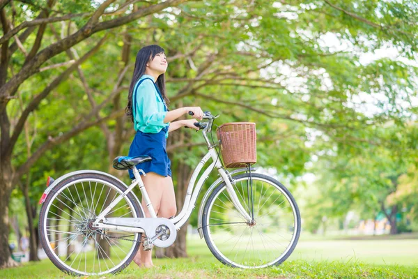 緑の芝生の上の夏の公園で自転車とアジアの若い女性 — ストック写真