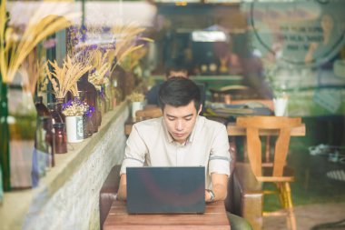 Dizüstü bilgisayarda çalışan ve gülümseyen yakışıklı genç Asyalı öğrenci adam