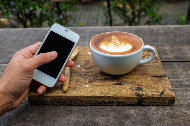 Smartphone latte sanat süt kahve ile ahşap arka plan, Clos iş nesne üzerinde doku bırakın