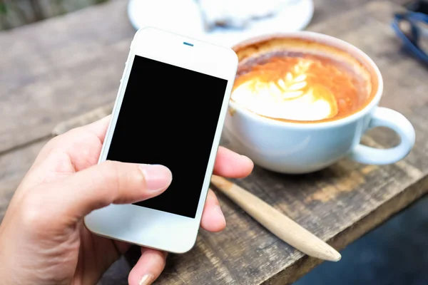 Smartphone con taza de café con leche arte latte dejar textura en wo — Foto de Stock