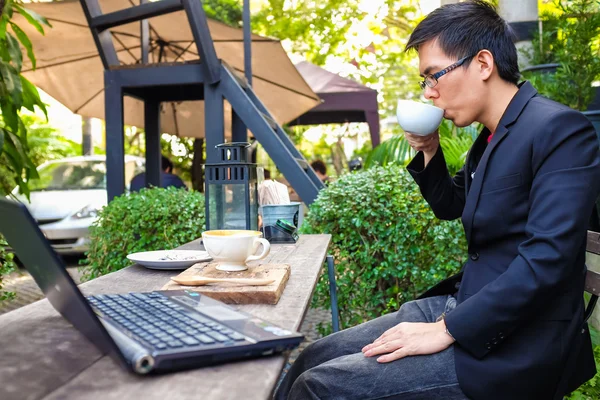 Latte kahve ile bir dizüstü bilgisayar kullanarak Asya iş adamı — Stok fotoğraf