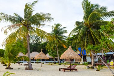 Lipe, Tayland Hindistan cevizi hurma ile dramatik bulutlu gökyüzü altında Andaman Denizi kıyısında ahşap şezlong standı