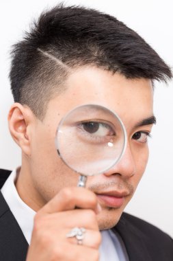 İş Asya adam arıyor, kamera aracılığıyla Büyüteç yakın çekim üzerine beyaz