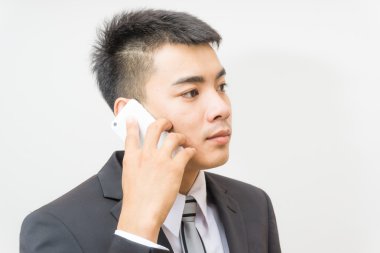 Beyaz arka plan üzerinde telefonda konuşan siyah elbiseli Asya adam yakışıklı iş