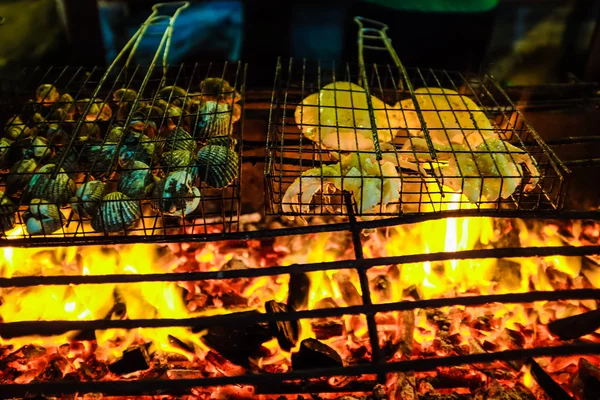 Rij heerlijke garnalen vissen en shell op grill met vlammen — Stockfoto