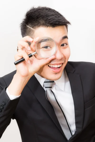 白のビジネス アジア男見てカメラを虫眼鏡をクローズ アップ — ストック写真