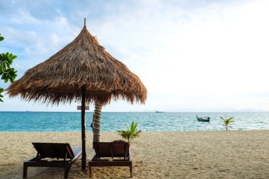 Güneş şemsiyesi ve tropik sahilde ahşap yataklar eğlence için en iyi yer. Deniz kıyı tatil