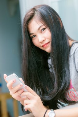 Güzel siyah Asyalı kadın yatağında döşeme telefonunda kullanma