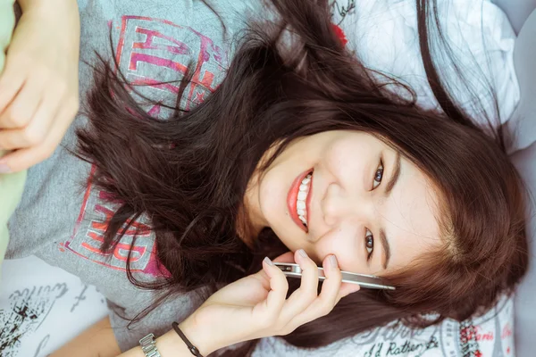 Schöne schwarze asiatische Frau mit auf ihr Telefon legen in ihr Bett — Stockfoto