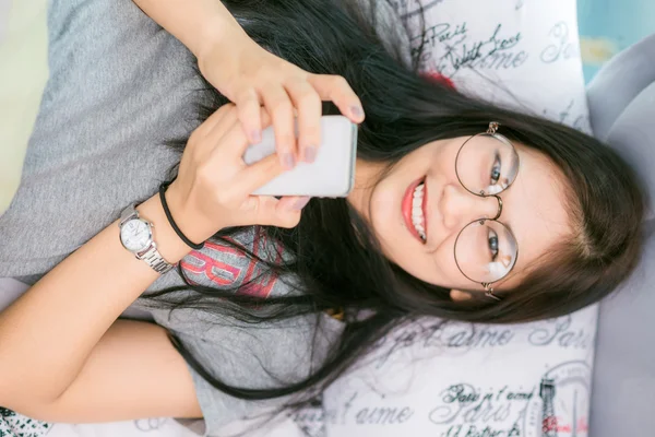 Frau im Bett checkt soziale Apps mit Smartphone — Stockfoto