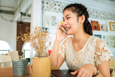 Asyalı güzel kız cep telefonu kafede konuşuyor.