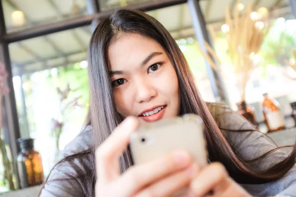 Charming asian woman with beautiful smile reading off touch phon — Stock Photo, Image
