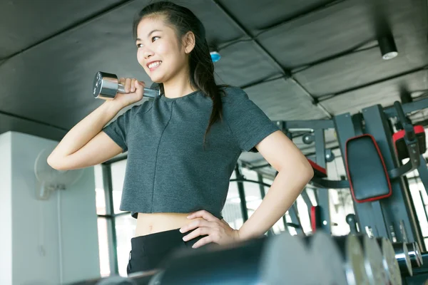 在健身房举杠铃在暗调的健身房训练的相当亚洲女孩的肖像 — 图库照片