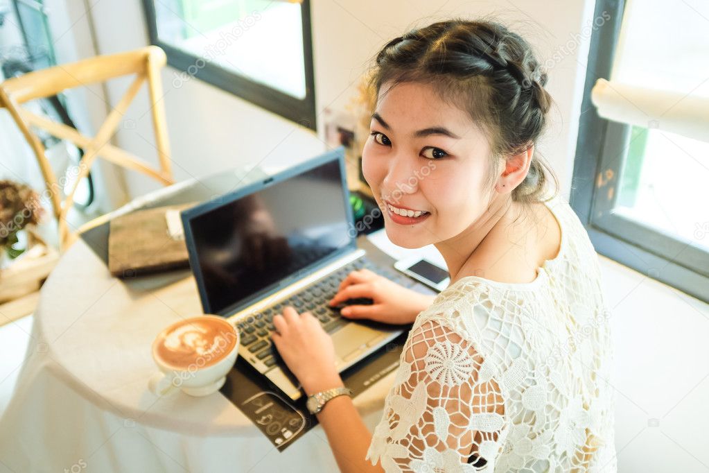 Overhead view of Beautiful young asian girl working at a coffee shop with a laptop, Young woman checking her business