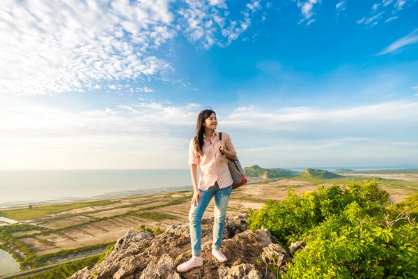 Young woman with backpack standing on a peak of cliff and enjoyi — Stock Photo, Image