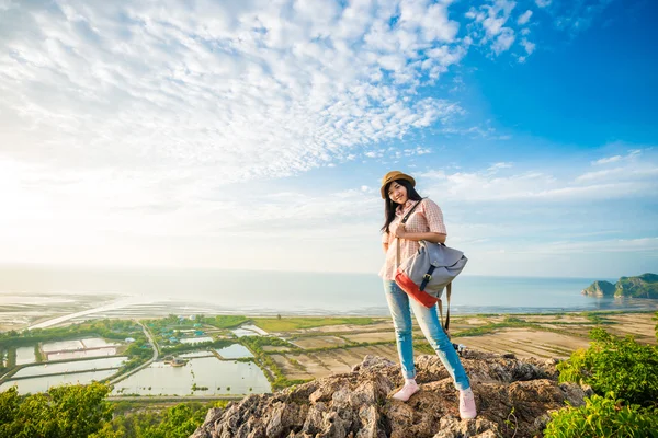 Young woman with backpack standing on a peak of cliff and enjoyi — Stock Photo, Image