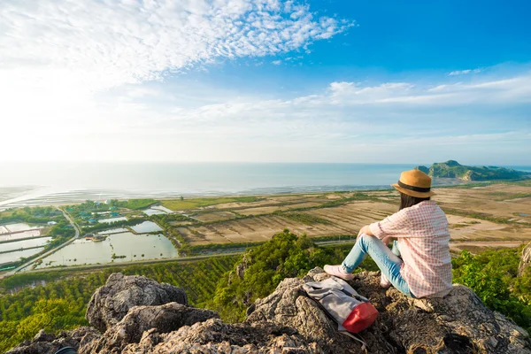 Asian hipster girl sitting on the peak of mountain with camera. — Stock Photo, Image